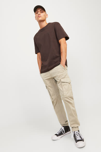 Pantalon cargo beige de JACK & JONES JEANS INTELLIGENCE, porté avec un t-shirt brun et des baskets noires.