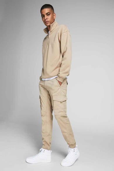 Pantalon cargo beige van JACK & JONES JEANS INTELLIGENCE, porté avec un pull beige à col zippé et des baskets montantes blanches.
