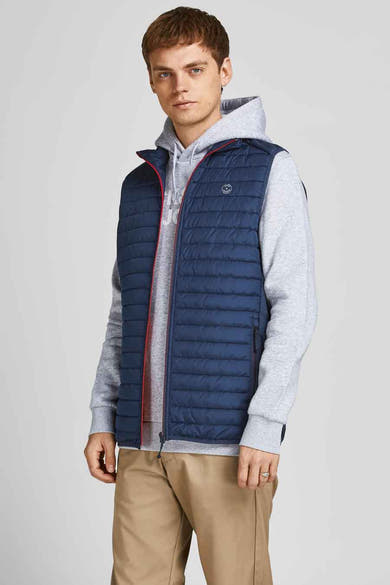 Blauwe mouwloze jas van JACK & JONES, gedragen over een grijze hoodie en een kaki broek.