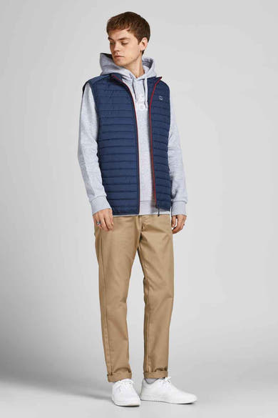Blauwe mouwloze jas van JACK & JONES, gedragen met een grijze hoodie en een beige chino broek.