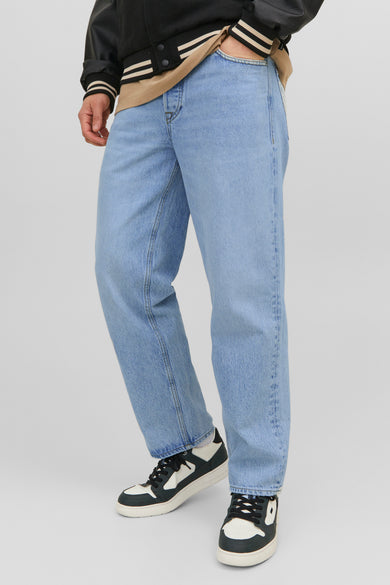 Jean large en denim bleu moyen de JACK & JONES JEANS INTELLIGENCE, porté avec un blouson aviateur et des baskets bicolores.