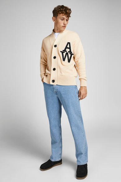 Jean large bleu clair de JACK & JONES JEANS INTELLIGENCE, porté avec un cardigan beige à écusson.
