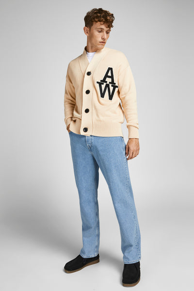 Jean large bleu clair de JACK & JONES JEANS INTELLIGENCE, porté avec un cardigan beige à écusson.