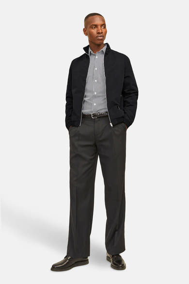 Veste courte noire de JACK & JONES, portée sur une chemise rayée et un pantalon sombre, poches apparentes.
