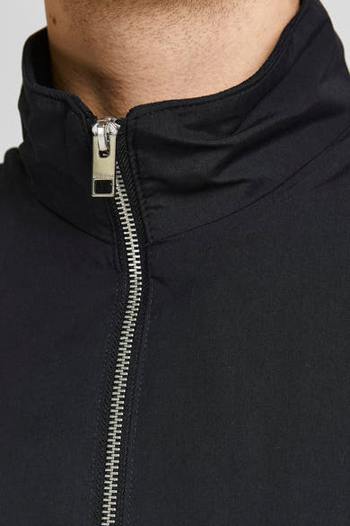 Korte zwarte jas van JACK & JONES met een zilveren ritssluiting aan de voorkant.