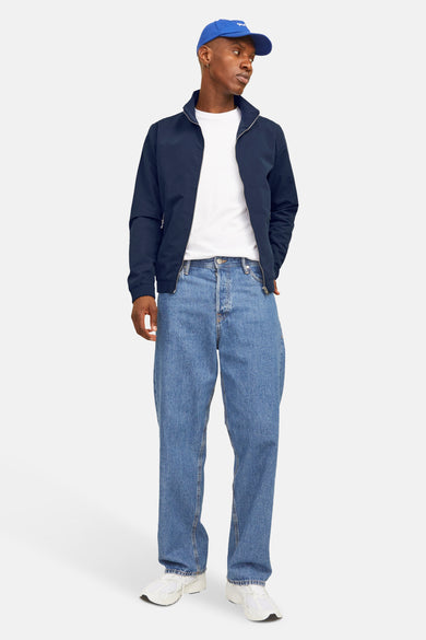 Veste courte bleue de JACK & JONES, portée sur un t-shirt blanc et un jean ample.