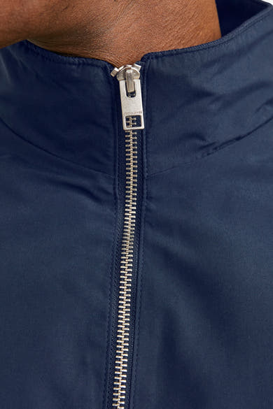 Korte blauwe jas van JACK & JONES, met een zichtbare zilveren ritssluiting aan de voorkant.
