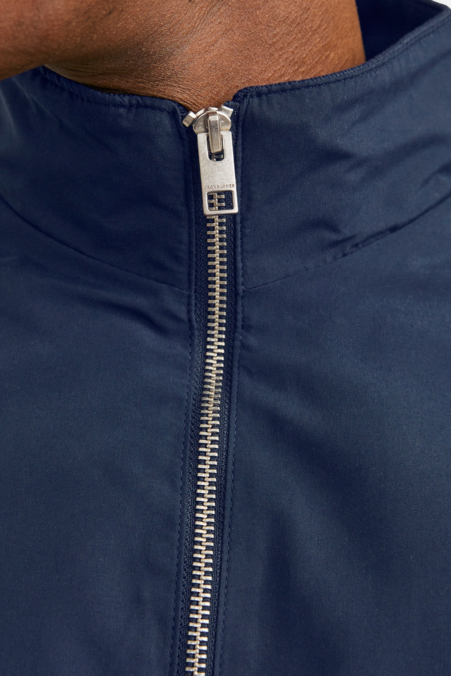 Korte blauwe jas van JACK & JONES, met een zichtbare zilveren ritssluiting aan de voorkant.