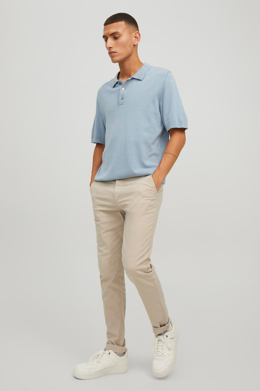Chino beige de JACK & JONES JEANS INTELLIGENCE, porté avec un polo bleu clair et des chaussures de sport blanches.