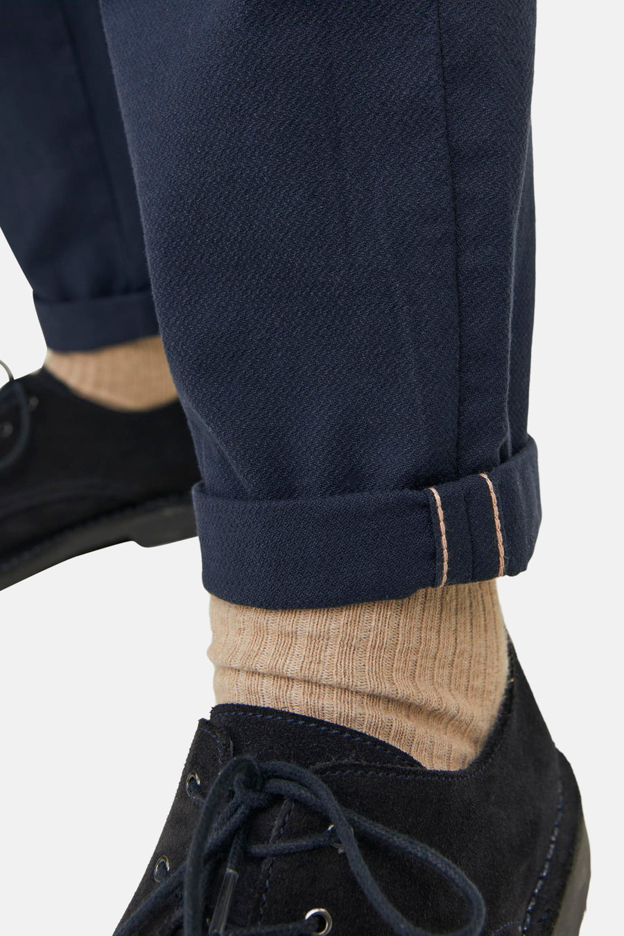 Chino bleu de JACK & JONES JEANS INTELLIGENCE, avec revers laissant apparaître une lisière selvedge, porté avec des chaussettes et des chaussures.