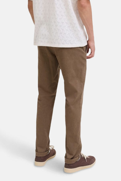 Chino beige par JACK & JONES JEANS INTELLIGENCE, porté avec un t-shirt blanc à motifs ajourés et des chaussures marron.