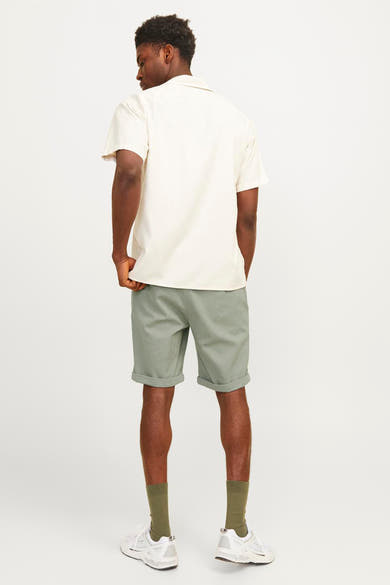 Korte groene JACK & JONES JEANS INTELLIGENCE, gedragen met een beige T-shirt, sokken en witte schoenen.