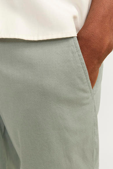 Kort groen JACK & JONES JEANS INTELLIGENCE vest met textuurpatroon, gedragen met een wit overhemd, hand in de zak.