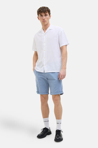 Korte blauwe van JACK & JONES JEANS INTELLIGENCE, gedragen met een wit overhemd en zwarte schoenen.