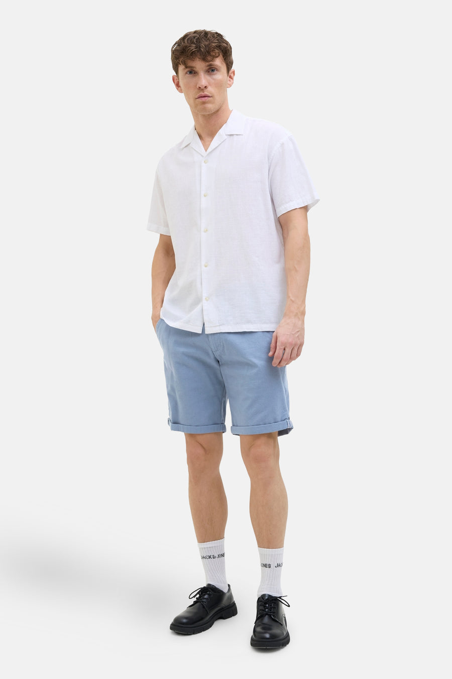Korte blauwe van JACK & JONES JEANS INTELLIGENCE, gedragen met een wit overhemd en zwarte schoenen.