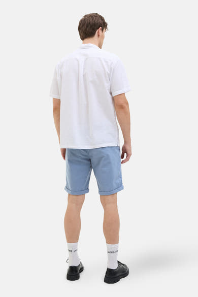Korte blauwe van JACK & JONES JEANS INTELLIGENCE, gedragen met een effen wit poloshirt en bedrukte witte sokken.