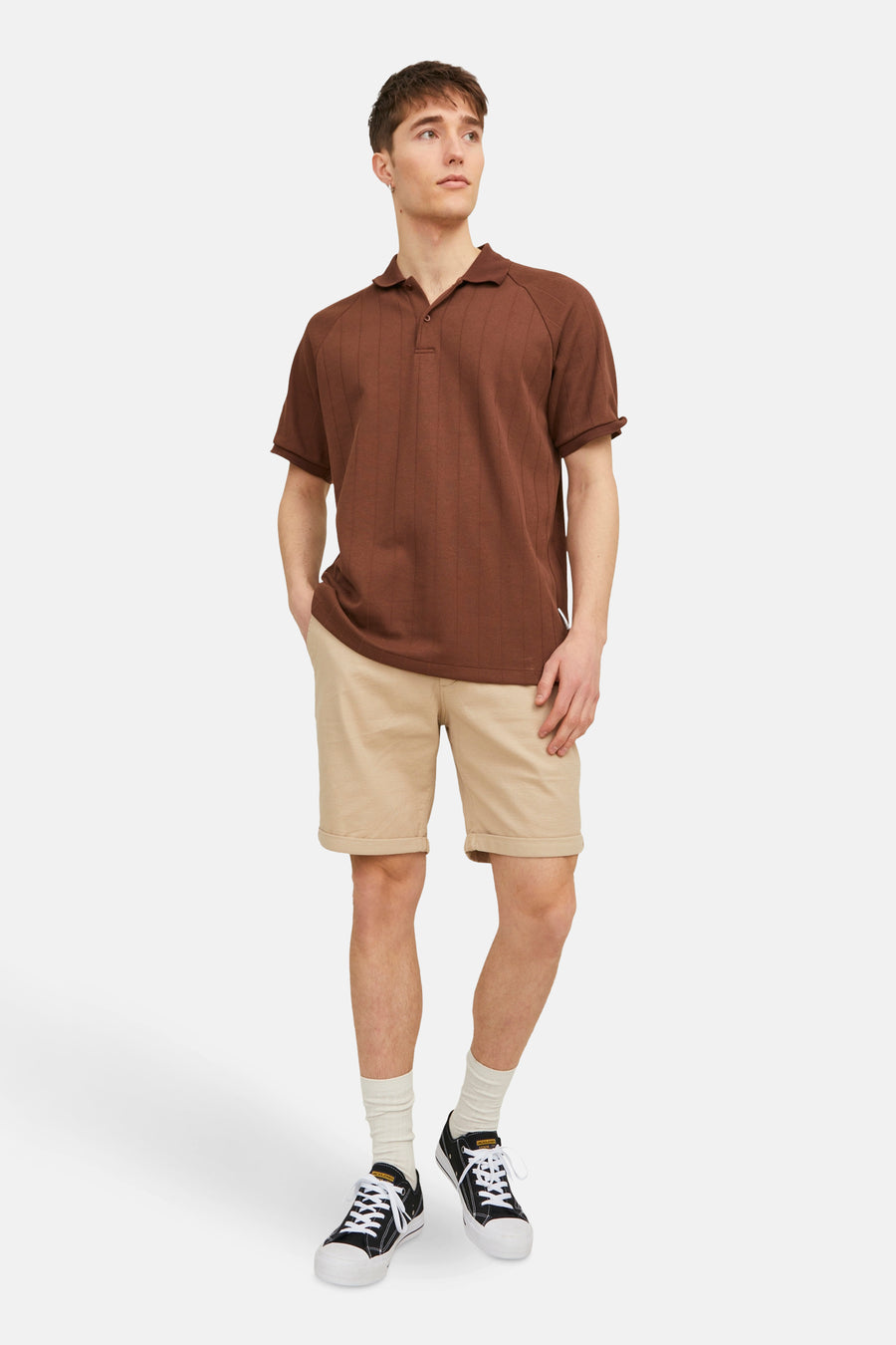 Korte beige JACK & JONES JEANS INTELLIGENCE gedragen met een bruin poloshirt en zwart-witte sneakers.