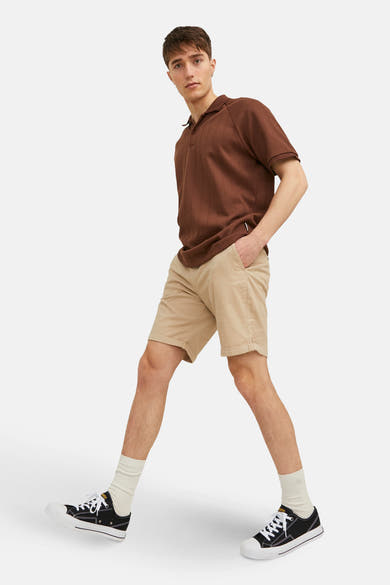 Korte beige short van JACK & JONES JEANS INTELLIGENCE, gedragen met een bruin poloshirt en zwarte sneakers.