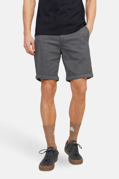 Short bleu de JACK & JONES JEANS INTELLIGENCE, avec ourlets retroussés et motif subtil, porté avec un t-shirt noir, des chaussettes marron et des baskets.
