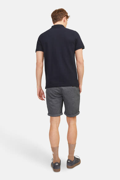 Short bleu de JACK & JONES JEANS INTELLIGENCE, porté avec un polo bleu marine, des chaussettes marron clair et des chaussures noires.