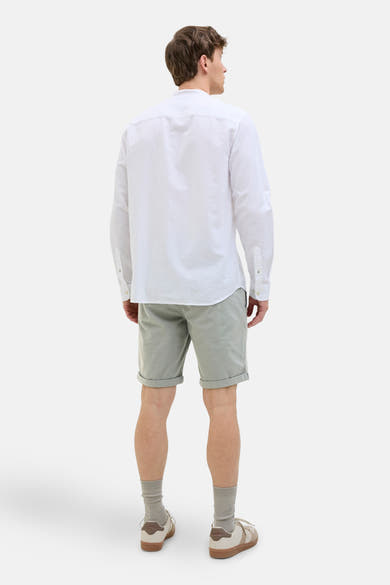 Korte groene broek van JACK & JONES JEANS INTELLIGENCE, met omgeslagen zoom, gedragen met een wit overhemd en sneakers.