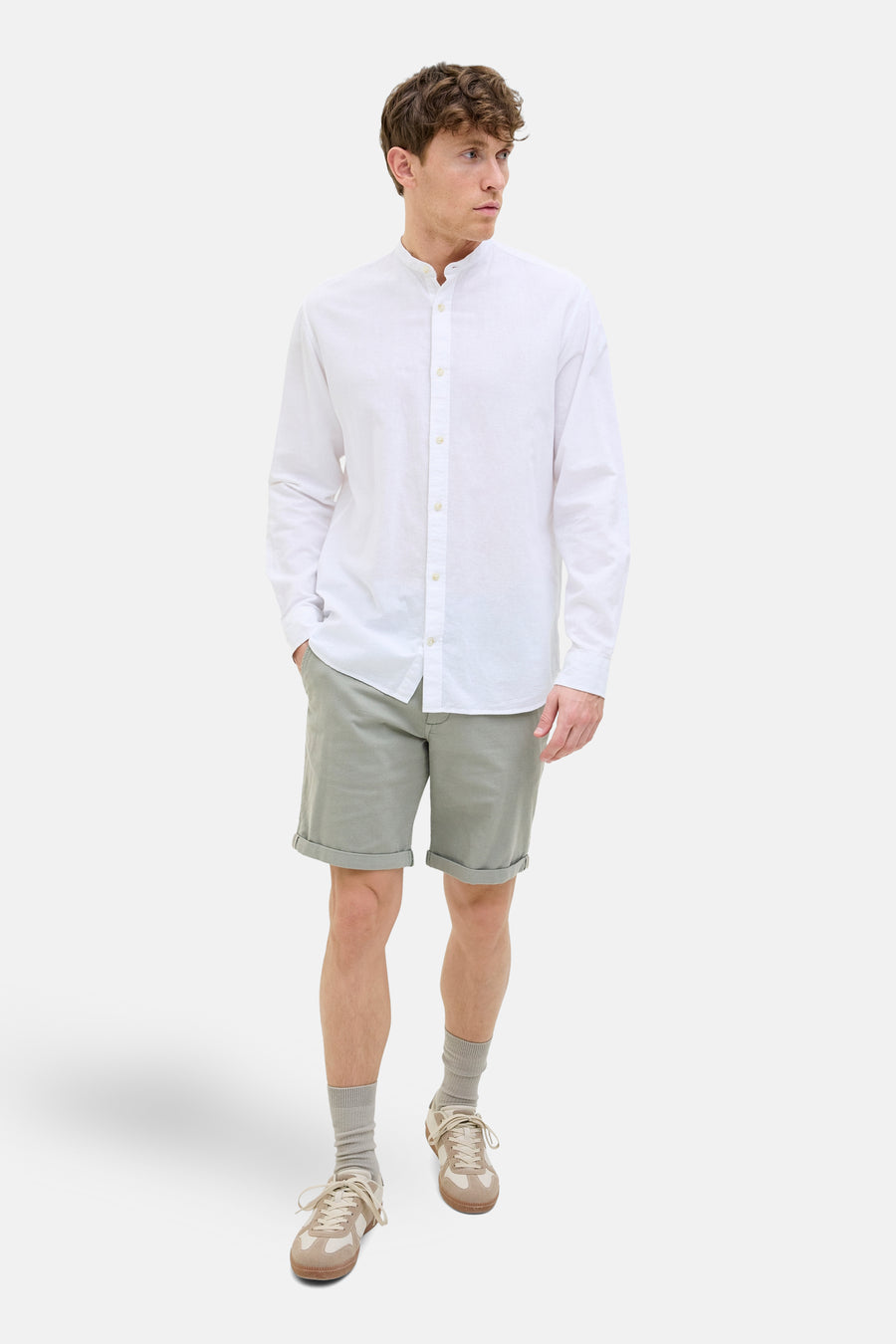Korte olijfgroene short JACK & JONES JEANS INTELLIGENCE, gedragen met een wit overhemd met lange mouwen en beige sneakers.