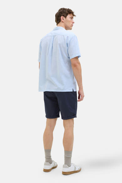 Short bleu de JACK & JONES JEANS INTELLIGENCE, porté avec une chemise bleu clair, des chaussettes grises et des baskets blanches.