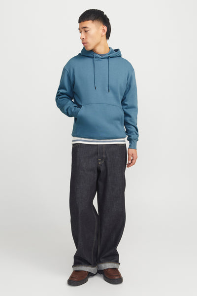 Blauwe hoodie, Originals by Jack & Jones, gedragen over een gestreept T-shirt en een donkere wijde jeans.