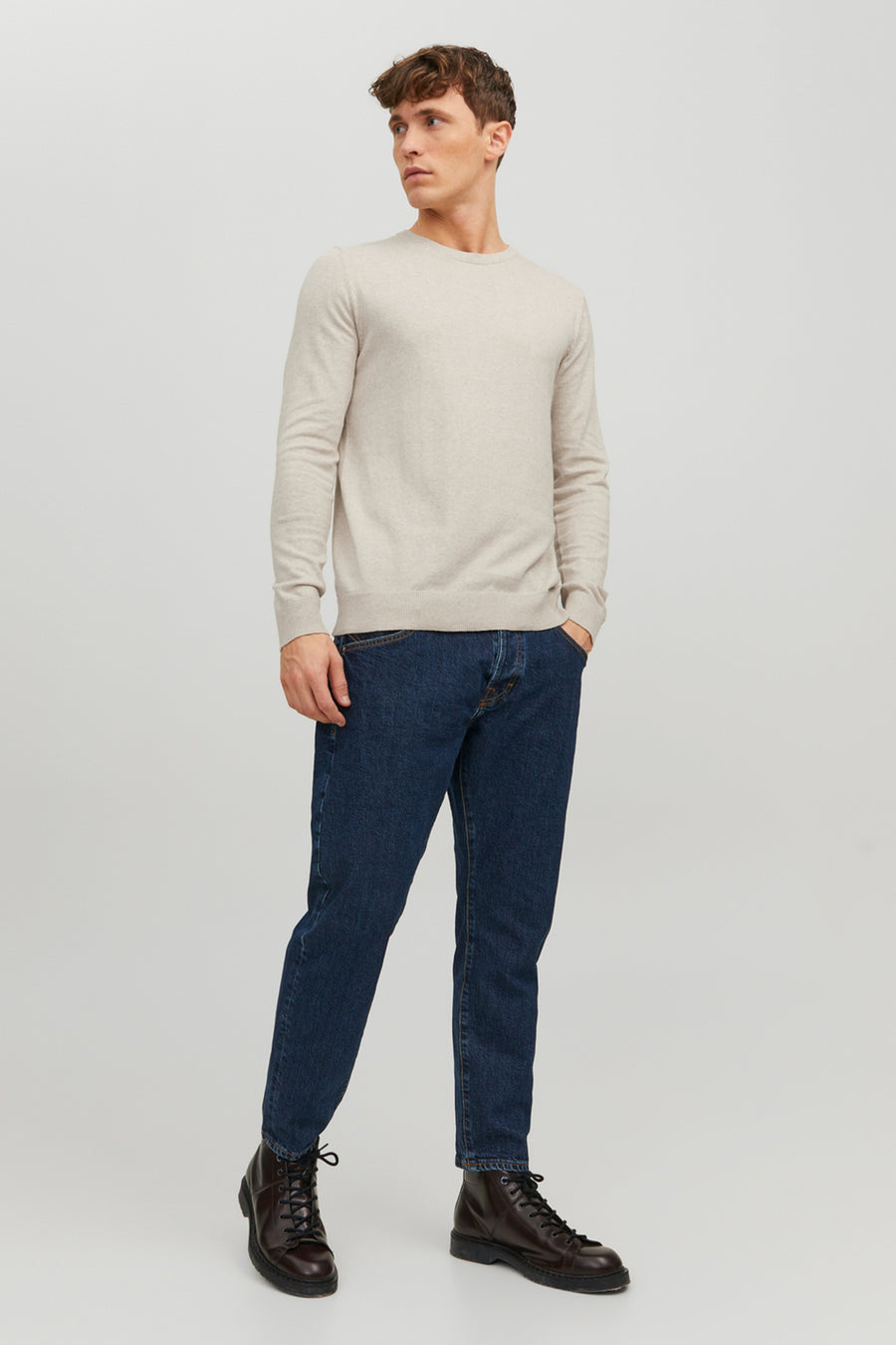 Pull beige de PREMIUM BLUE by JACK & JONES, porté avec un jean bleu foncé et des bottes en cuir marron, en vue de face.
