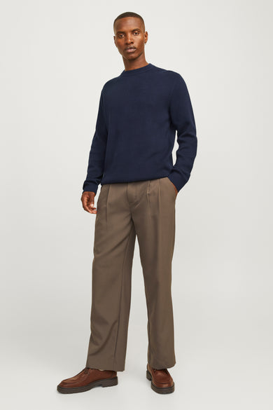 Blauwe rondehalspullover van PREMIUM BY JACK & JONES, gedragen met een gerimpeldebrubruine broek en bruine lederen schoenen.