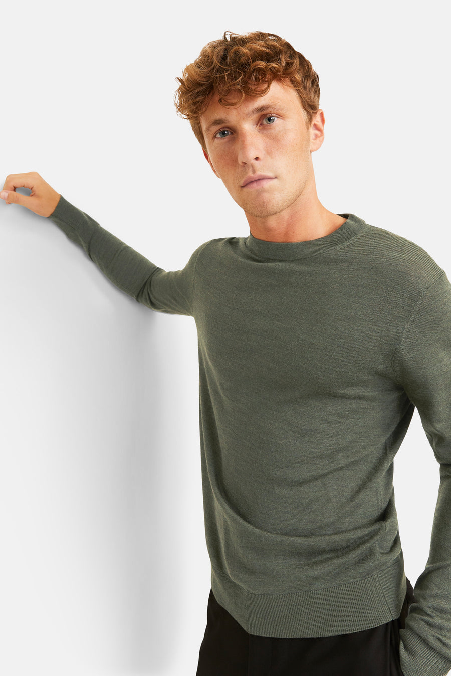 Kaki ronde hals trui van PREMIUM by JACK & JONES, gedragen met een zwarte broek, op een effen witte achtergrond.