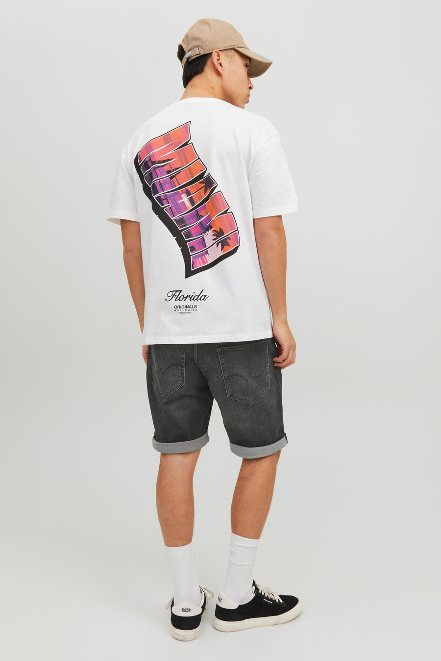 Short en denim noir par JACK & JONES JEANS INTELLIGENCE, avec ourlet retroussé, porté avec un t-shirt blanc et une casquette beige.