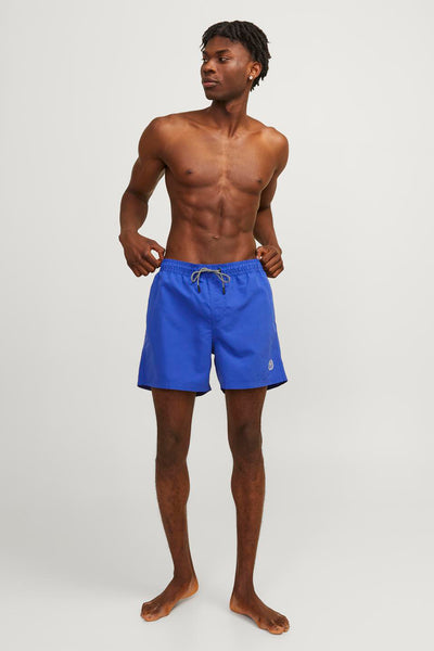 Short de bain bleu par JACK & JONES JEANS INTELLIGENCE, porté par un homme torse nu.