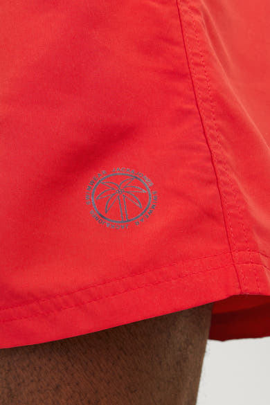 Rode zwembroek van JACK & JONES JEANS INTELLIGENCE met palmboomlogo op de zijkant.