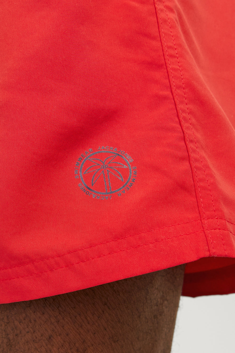 Rode zwembroek van JACK & JONES JEANS INTELLIGENCE met palmboomlogo op de zijkant.