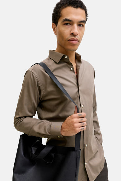 Bruin overhemd met lange mouwen, van PREMIUM by JACK & JONES, gedragen met een zwarte schoudertas.