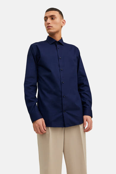 Chemise bleu marine à manches longues de PREMIUM by JACK & JONES, portée avec un pantalon beige ample.