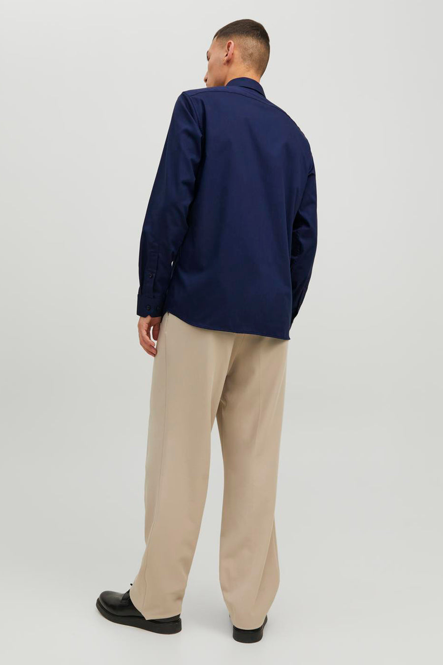 Blauwe blouse met lange mouwen van PREMIUM by JACK & JONES, van achteren gezien, gedragen met een wijde beige broek en zwarte schoenen.