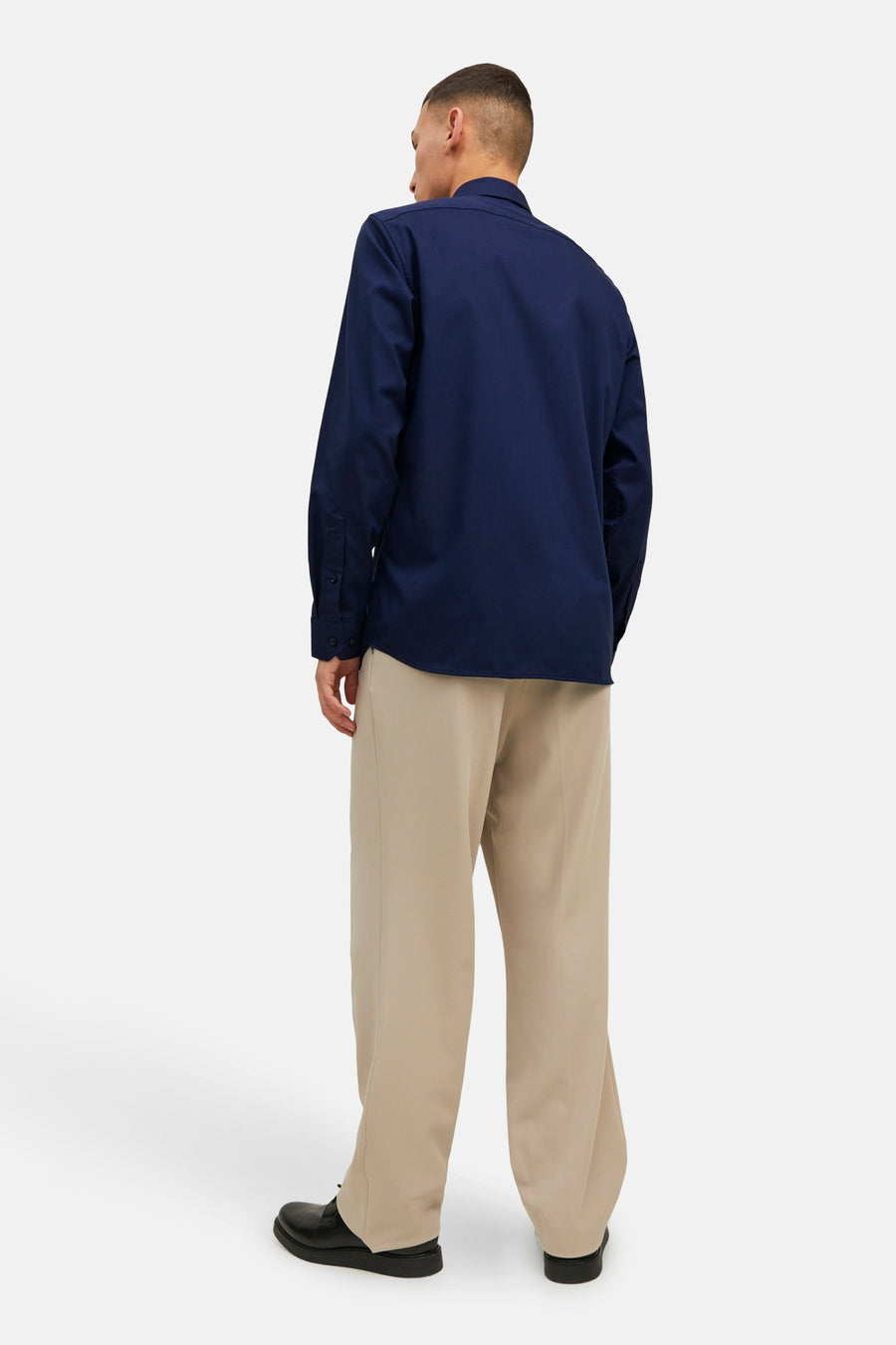 Marineblauwe blouse met lange mouwen van PREMIUM by JACK & JONES, van achteren gezien met een beige broek en zwarte schoenen.