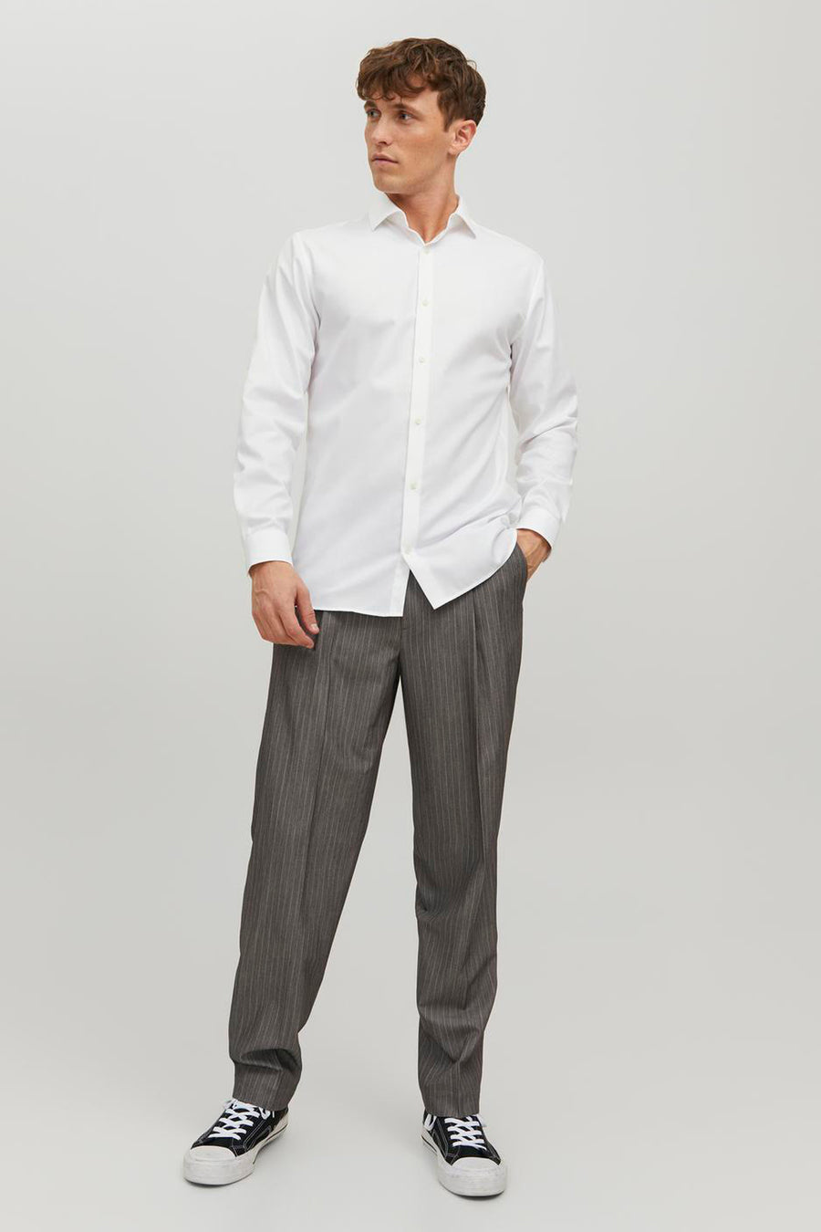 Wit overhemd met lange mouwen van PREMIUM by JACK & JONES, gedragen met een gestreepte broek en sneakers.