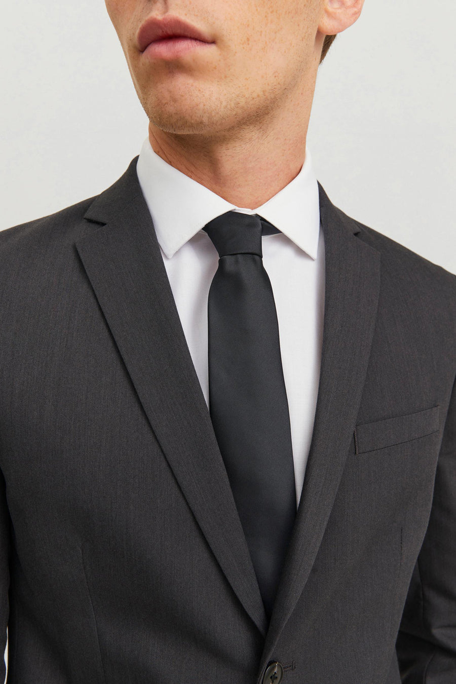 Cravate noire par ACCESSORIES BY JACK & JONES, portée avec une chemise blanche et un costume anthracite.