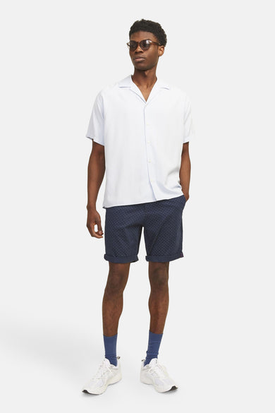 Short bleu marine à pois blancs de JACK & JONES JEANS INTELLIGENCE, porté avec une chemise blanche et des chaussures de sport blanches.