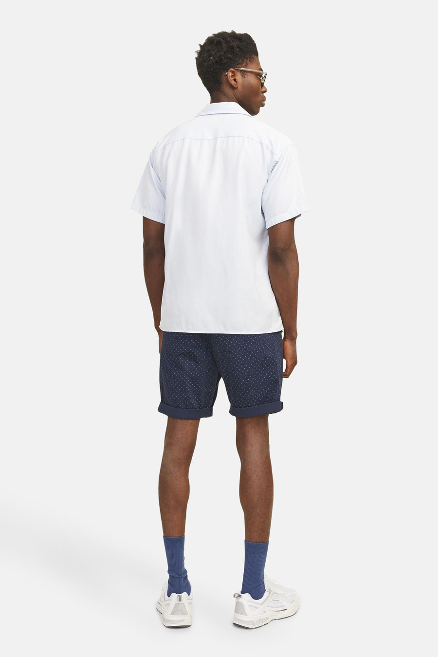 Short bleu marine à pois blancs de JACK & JONES JEANS INTELLIGENCE, porté avec une chemise blanche, des chaussettes bleues et des baskets blanches.