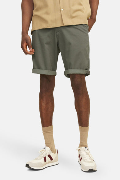 Short olive JACK & JONES JEANS INTELLIGENCE avec ourlet retroussé, porté avec des chaussettes et des baskets.
