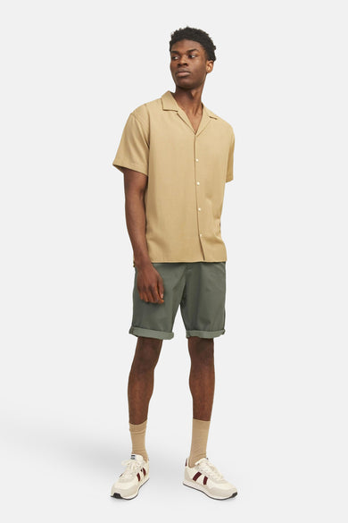 Short olive van JACK & JONES JEANS INTELLIGENCE, porté avec une chemise beige, des chaussettes et des baskets.