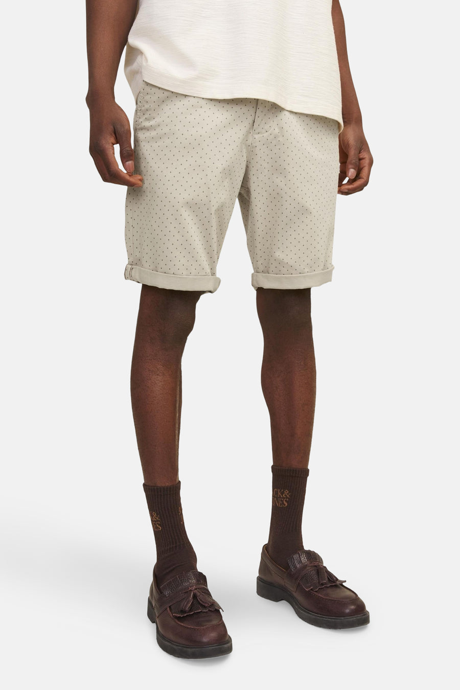 Korte beige JACK & JONES JEANS INTELLIGENCE, met subtiele patronen, gedragen met een gebroken wit T-shirt, bruine sokken en loafers.