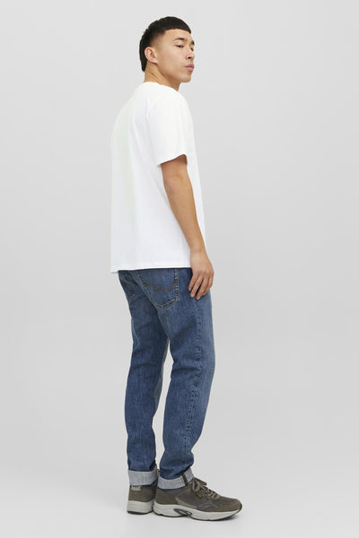 Wit T-shirt van JACK & JONES, gedragen met een blauwe jeans en bruine sneakers, zijwaarts gezien.