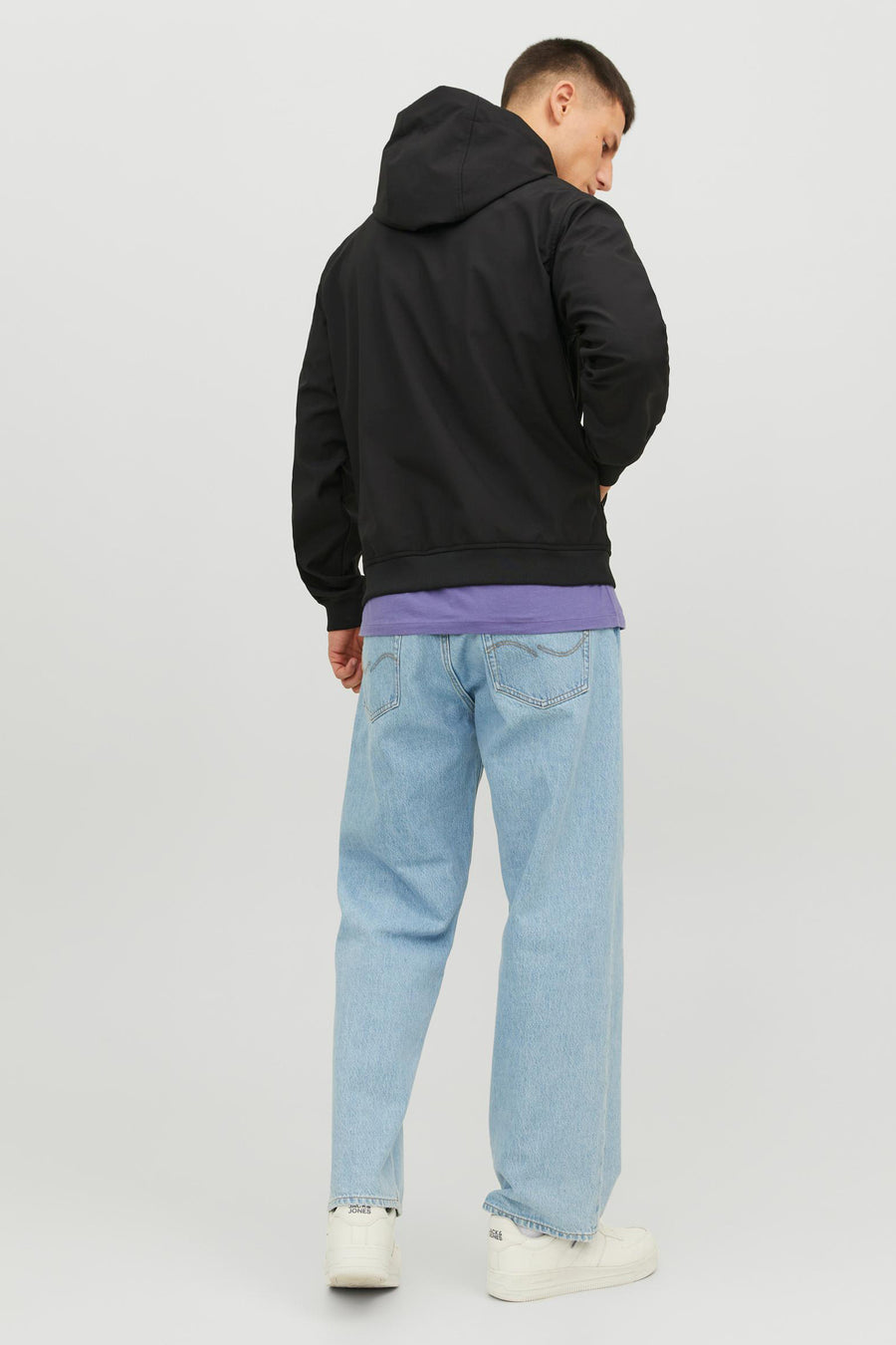Veste courte noire de JACK & JONES, avec une capuche, portée avec un t-shirt violet et un jean bleu clair.