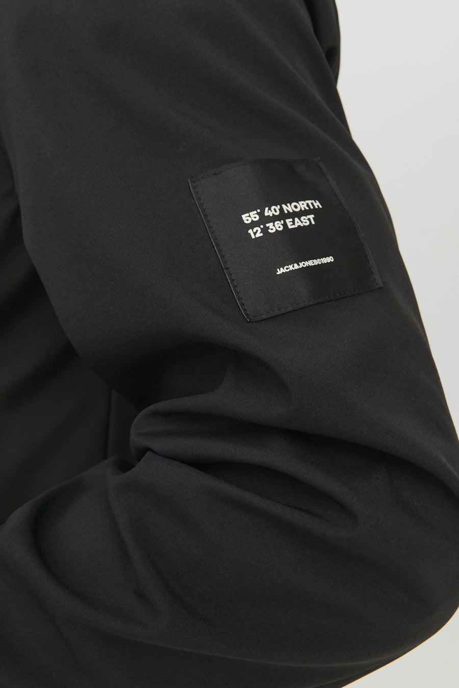 Veste courte noire de JACK & JONES, avec inscription des coordonnées géographiques.