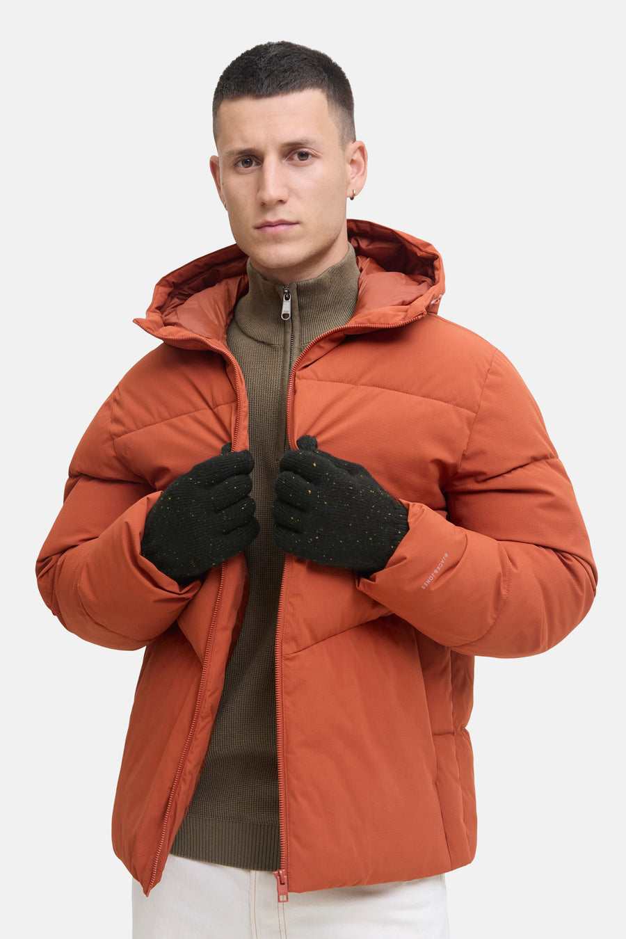 Gants noirs par ACCESSORIES BY JACK & JONES, avec mouchetures dorées, portés avec un pull col roulé marron et une veste orange.